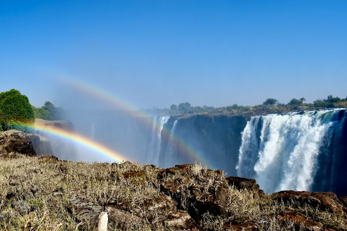 A rainbow in the sky over a waterfall